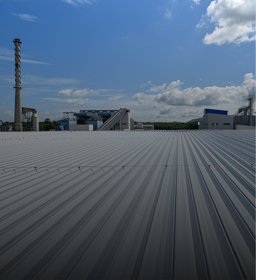 Industrial rooftop with chimney under blue sky.