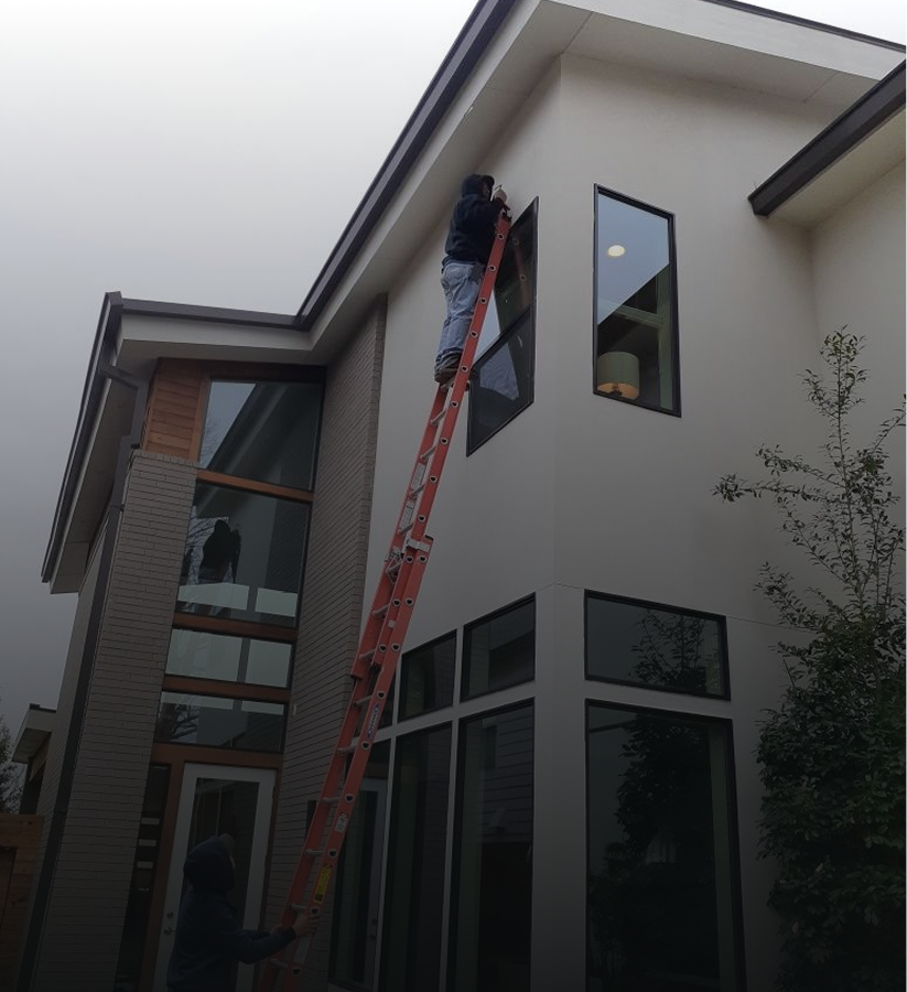 Person on ladder fixing house exterior.