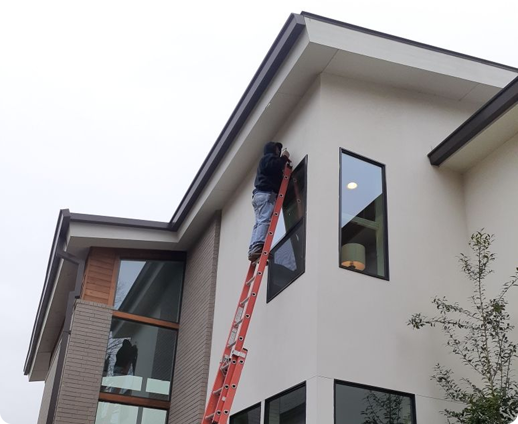 Person on ladder inspecting house exterior.